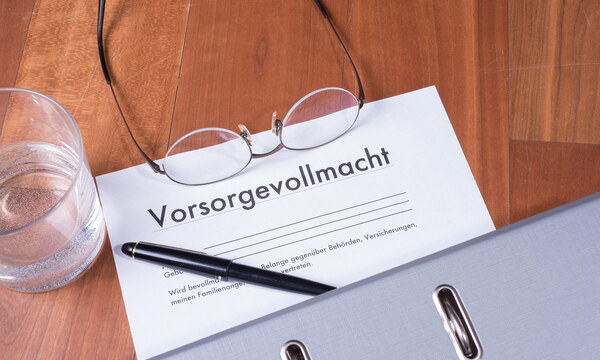 Ein Blatt mit der Überschrift „Vorsorgevollmacht“ liegt auf einem Tisch, darauf liegen eine Brille, ein Kugelschreiber und ein Aktenordner.