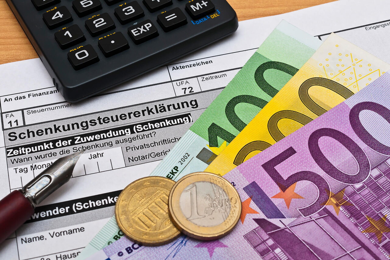 Geldscheine und Münzen liegen auf einer Schenkungssteuererklärung für das Finanzamt