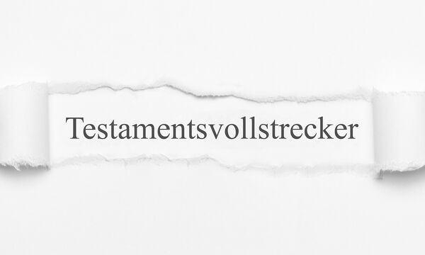 Ein Bogen Papier, in dessen Mitte ein Loch gerissen wurde. In diesem Loch befindet sich Text in Serifenschrift: "Testamentsvollstrecker".